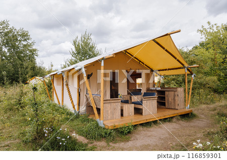 Cozy open glamping tent with light inside. Camping tent for outdoor summer holiday and vacation Cozy open glamping tent with light inside. Camping tent for outdoor summer holiday and vacation 116859301