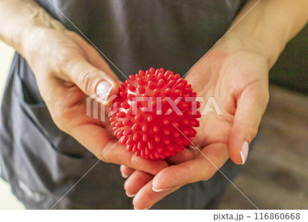 Shot of the female doctor manual therapist holding portable massage ball, Showing how to apply pressure with it Shot of the female doctor manual therapist holding portable massage ball, Showing how to apply pressure with it 116860668
