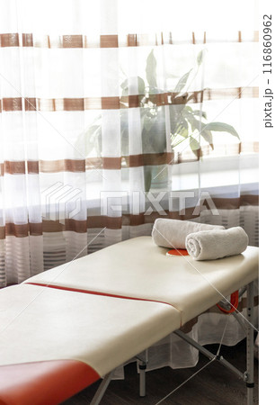 Close up shot of the white towels rolled in the massage couch. Close up shot of the white towels rolled in the massage couch. 116860962