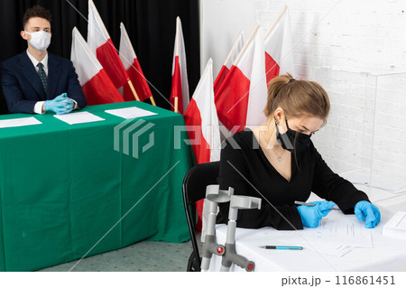 A teenager with orthopedic crutches sits at the polling station and fills out ballots for the president of Poland. A teenager with orthopedic crutches sits at the polling station and fills out ballots for the president of Poland. 116861451