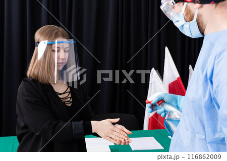 A woman from an election commission disinfects her hands before sitting at an election table. 116862009