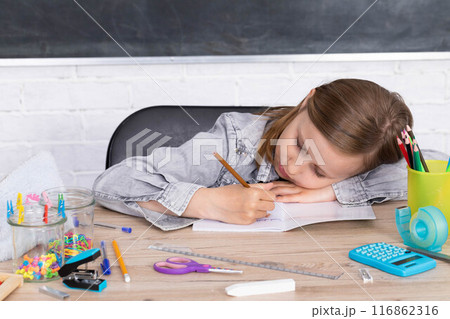 The student draws with crayons in the teddy bear school notebook as the subject of today's lesson. The student draws with crayons in the teddy bear school notebook as the subject of today's lesson. 116862316