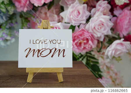 Happy Mother's day with I love you, MOM text write on paper card with wooden easel and flowers decoration on wooden background 116862665
