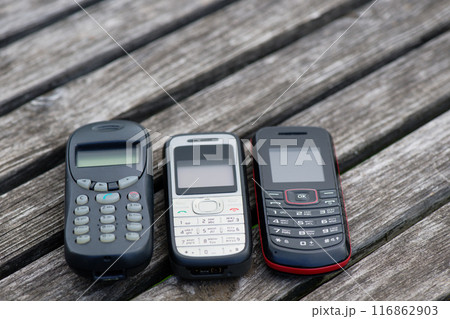 Old cell phones on wooden table 116862903