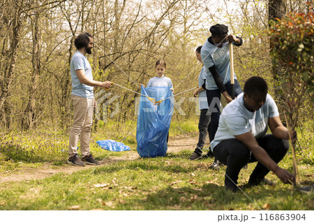 People collaborating to use proper tools and clean the forest, recycling plastic waste and fighting pollution. Activists team volunteering to collect rubbish from the woodland ecosystem. 116863904