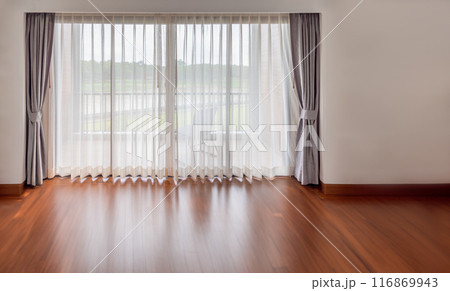 Interior of empty living room with large bright window and white curtains in empty room 116869943