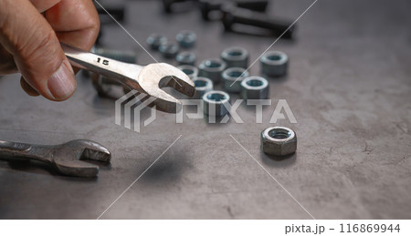Mechanic hand holding socket wrench on steel work bench 116869944