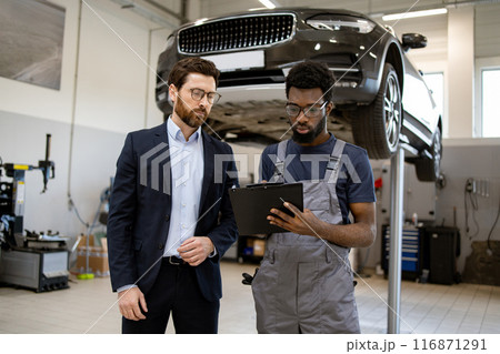 Mechanic discussing car repair with customer in auto shop 116871291
