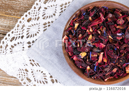 Tea mix of karkade, flowers and berries in a saucer and on the textile. Tea mix of karkade, flowers and berries in a saucer and on the textile. 116872016