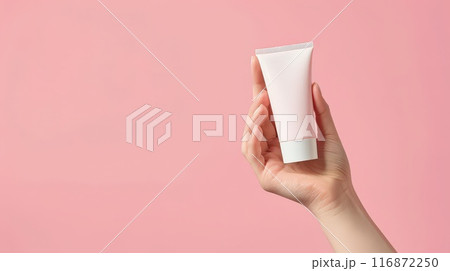 Hand holding cream tube with soft pastel background for beauty and skincare advertisement Hand holding cream tube with soft pastel background for beauty and skincare advertisement 116872250