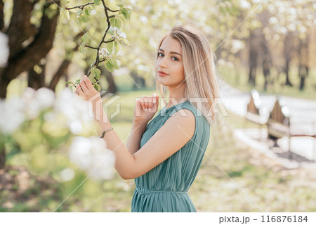 Spring portrait of an adult happy woman in a blooming garden, May flowers girl 116876184