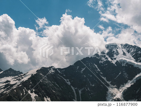 Stunning snow-covered mountain peaks under dramatic cloudy sky during daytime hiking adventure 116877900