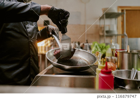 Unrecognizable chef hands flipping beef steak on frying pan Unrecognizable chef hands flipping beef steak on frying pan 116879747