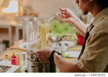 Young sous chef cooking handmade pasta in modern restaurant kitchen Young sous chef cooking handmade pasta in modern restaurant kitchen 116879765