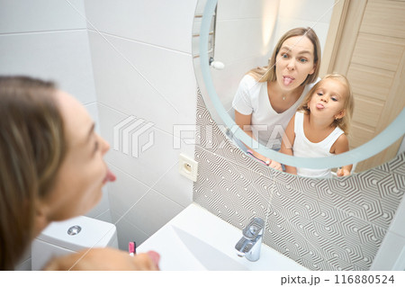 mother and little baby daughter sticking out their tongue mother and little baby daughter sticking out their tongue 116880524