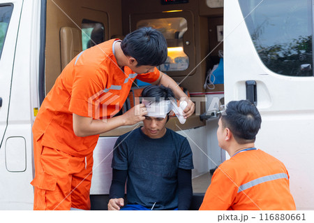 A man with a bandaged head is being helped by two other men in orange. The scene is serious and focused on the injured man A man with a bandaged head is being helped by two other men in orange. The scene is serious and focused on the injured man 116880661