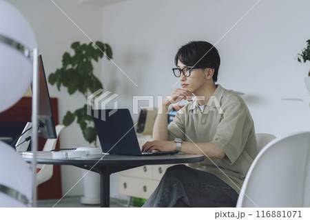 パソコンで作業をするメガネをかけた20代の男性 116881071