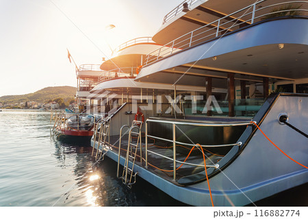 Line of many luxury smal cruise yacht boat ship docked Croatian bay harbor shore blue  clear water bright summer sunny sunset sunrise morning. Rich quality lifestyle. Boat vessel charter service 116882774