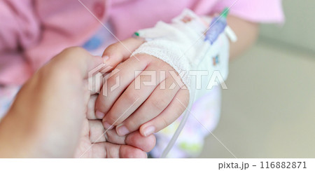 Mother holding child hand with saline IV solution in hospital 116882871