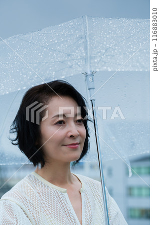 降りしきる雨の中、力強く傘をさすミドル女性 降りしきる雨の中、力強く傘をさすミドル女性 116883010