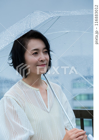 降りしきる雨の中、力強く傘をさすミドル女性 降りしきる雨の中、力強く傘をさすミドル女性 116883012