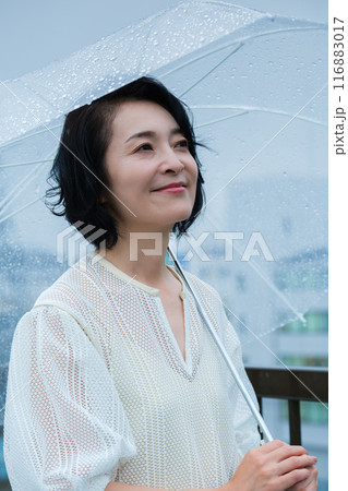 降りしきる雨の中、力強く傘をさすミドル女性 116883017