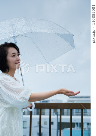降りしきる雨の中、力強く傘をさすミドル女性 降りしきる雨の中、力強く傘をさすミドル女性 116883081