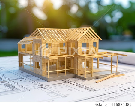 a detailed model of a house under construction placed on top of architectural blueprints 116884389