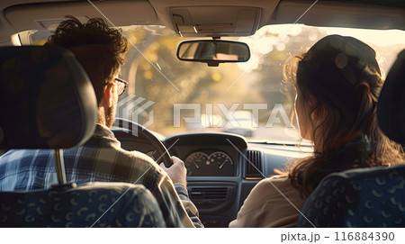 view from the back seat of a car, with a man driving and a woman sitting in the passenger seat 116884390
