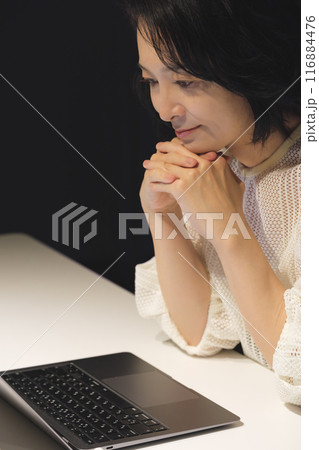 夜、パソコンに向かって作業するミドル女性 116884476