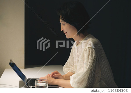 夜、パソコンに向かって作業するミドル女性 116884508