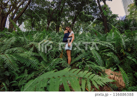 Portrait of Mother with her cute baby in park between fern leaves 116886388