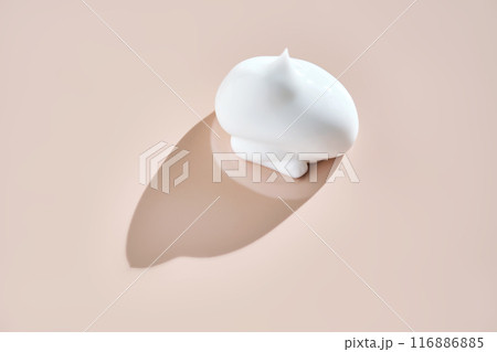 A smear of white cream on a beige background. 116886885