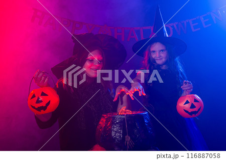 Two witches having fun together. Kid and mother conjure on magic pot. Halloween autumn holiday concept 116887058