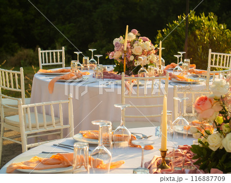 Beautiful outdoor wedding decoration in city. Candles and dried flowers and accessories with bouquets and glasses on table with linen tablecloth on newlywed table on green lawn Beautiful outdoor wedding decoration in city. Candles and dried flowers and accessories with bouquets and glasses on table with linen tablecloth on newlywed table on green lawn 116887709