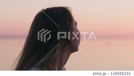 teenage girl standing on a beach at sunset teenage girl standing on a beach at sunset 116888232
