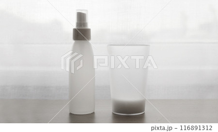 A plastic bottle with a pulivizer and a glass in front of the window. A plastic bottle with a pulivizer and a glass in front of the window. 116891312