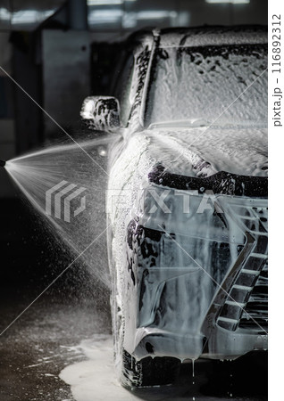 Man applying foam to black car in car wash. Vertical photo. Man applying foam to black car in car wash. Vertical photo. 116892312