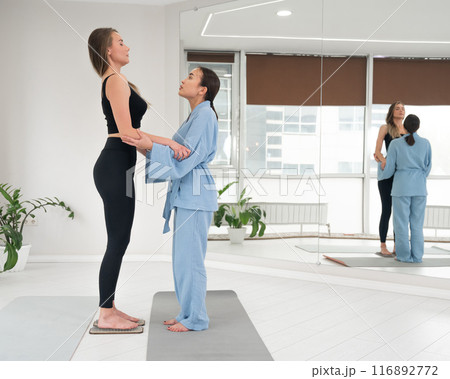 Caucasian woman stands on sadhu boards with therapist support. 116892772