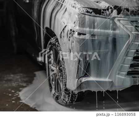Foam drips from the bumper of a black car. Car wash.  Foam drips from the bumper of a black car. Car wash.  116893058