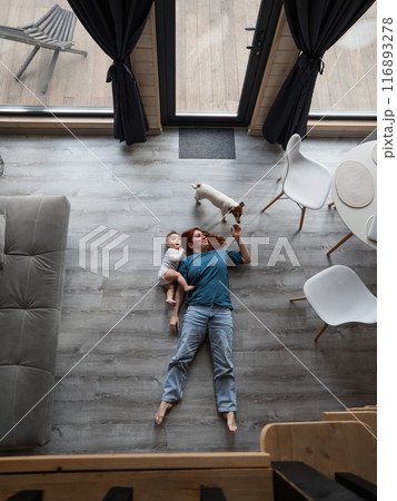 Top view of caucasian woman lying on floor with son and jack russell terrier dog. Vertical photo.  116893278