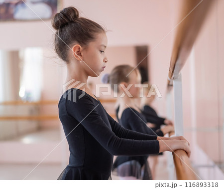 Cute little girls in black swimsuits and tutu do ballet at the barre. Cute little girls in black swimsuits and tutu do ballet at the barre. 116893318