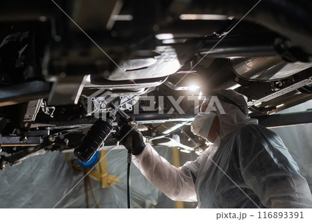 The master sprays an anti-corrosion compound on the bottom of the car. The master sprays an anti-corrosion compound on the bottom of the car. 116893391