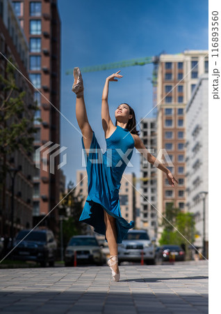 Beautiful Asian ballerina in blue dress posing in splits outdoors. Urban landscape. Vertical photo. Beautiful Asian ballerina in blue dress posing in splits outdoors. Urban landscape. Vertical photo. 116893560
