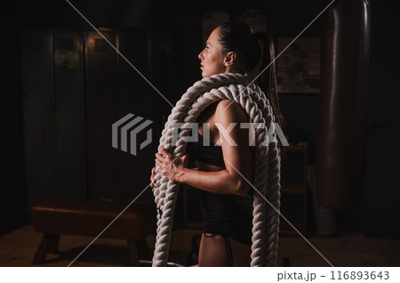 Caucasian woman posing with ropes in retro gym. Caucasian woman posing with ropes in retro gym. 116893643