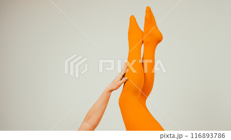 Female legs in ocher tights on a white background. Copy space.  Female legs in ocher tights on a white background. Copy space.  116893786