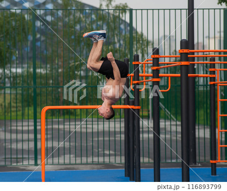 Young shirtless male athlete doing backflip on outdoor sports ground. Young shirtless male athlete doing backflip on outdoor sports ground. 116893799