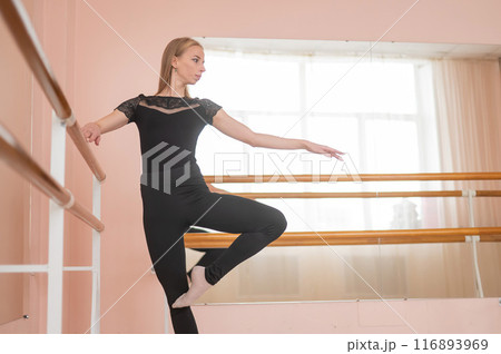 Caucasian blonde woman is practicing ballet in class. Ballerina rehearsing at the barre.  116893969