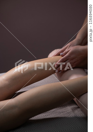 Close-up of a woman's leg massage in a salon. Vertical photo. 116894080