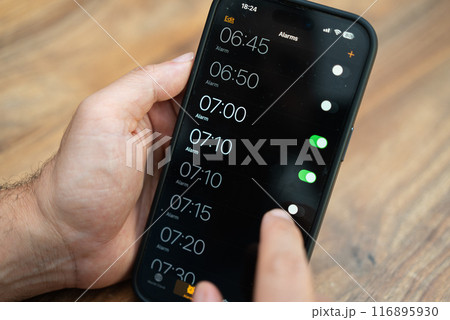 Male person hand selects appropriate time activating alarm clock on modern smartphone to wake up timely in morning preparing for productive working day 116895930